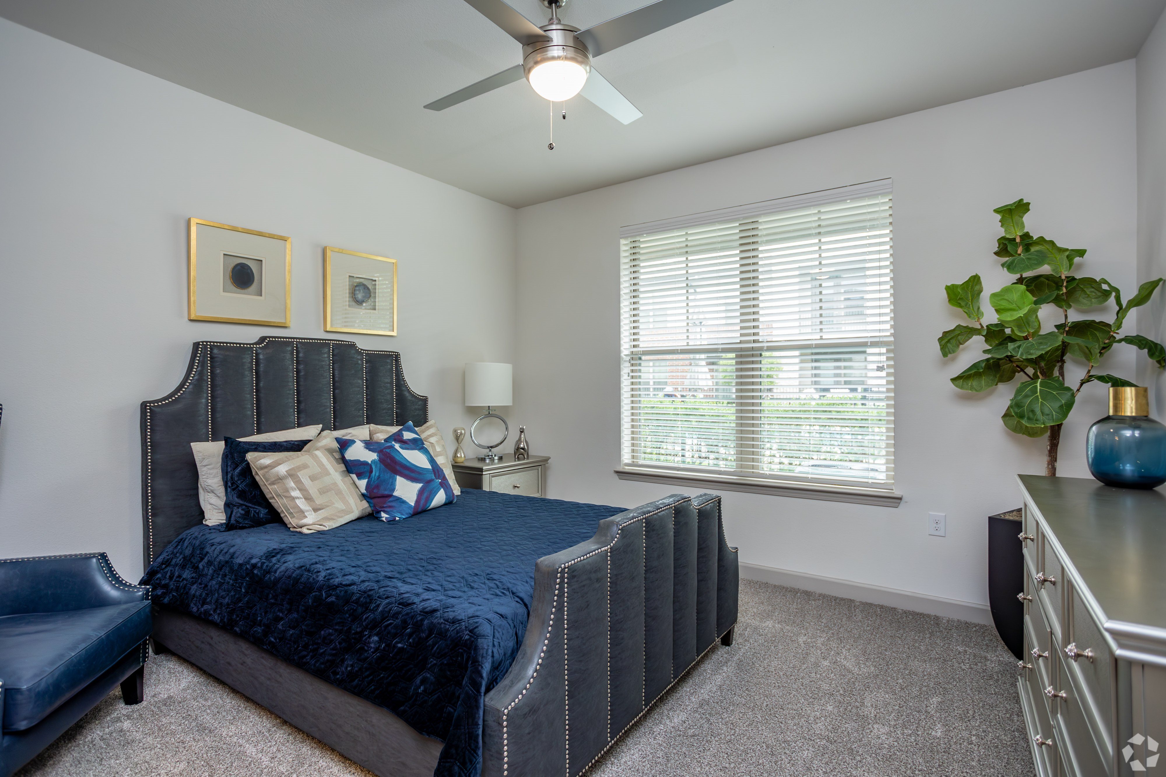 A bedroom with a bed, chair, and ceiling fan.